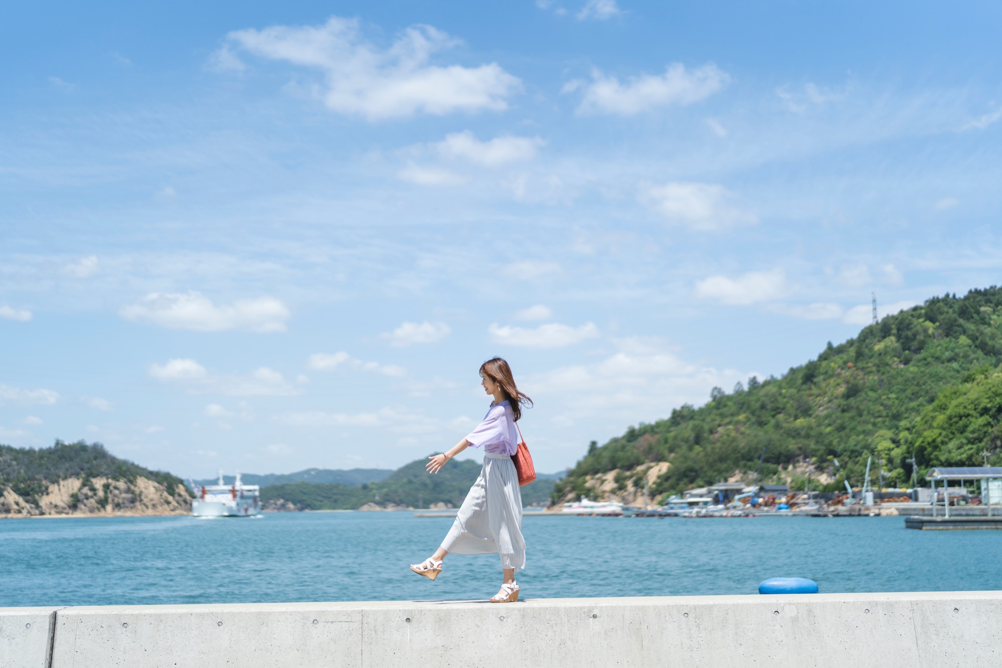 海辺の堤防を歩く旅人
